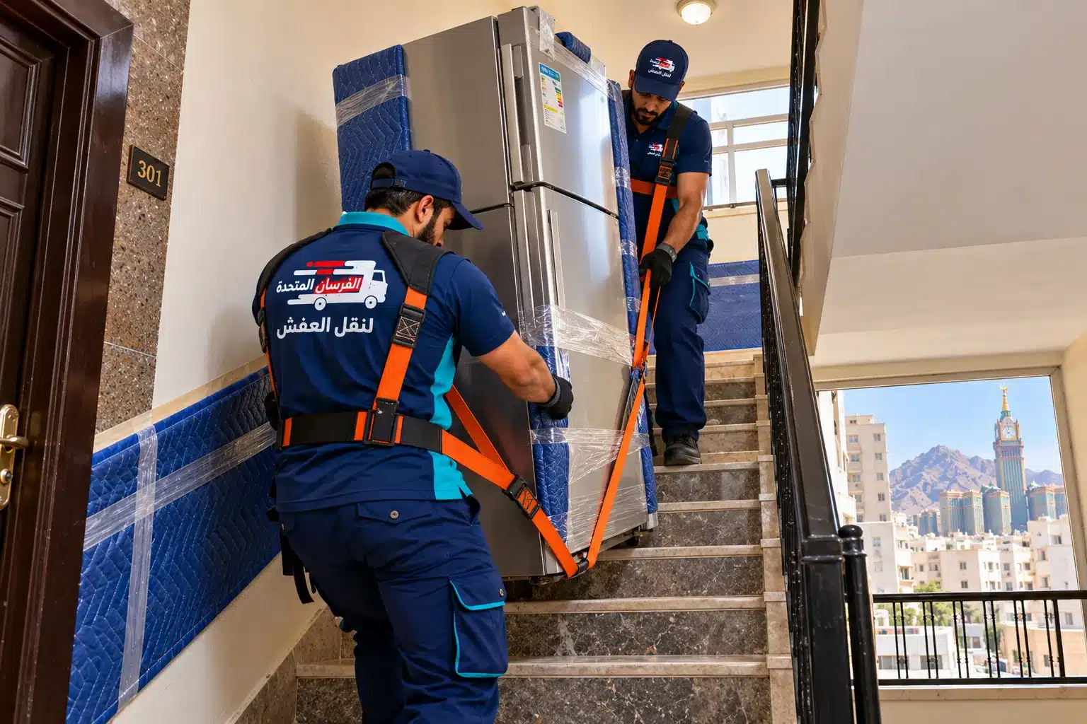 عمال ينقلون ثلاجة على درج عمارة في حي الرصيفة بمكة بأحزمة حمل